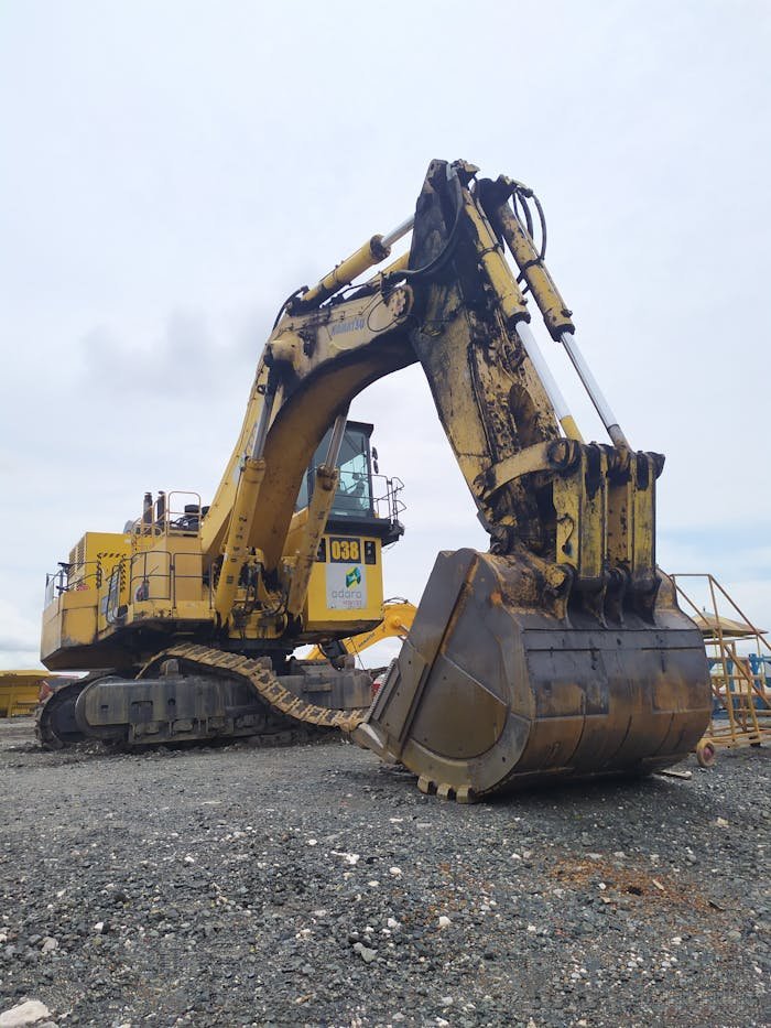 Services Large yellow excavator at a construction site in Indonesia under a cloudy sky.